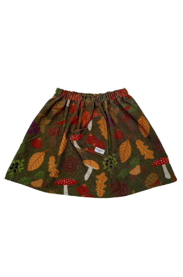 Brooke skirt 1 is a botanical print elasticized waist skirt for girls made in organic cotton corduroy. The print shows autumn leaves, berries, nuts and mushrooms. On the right side there is a heart shaped pocket.