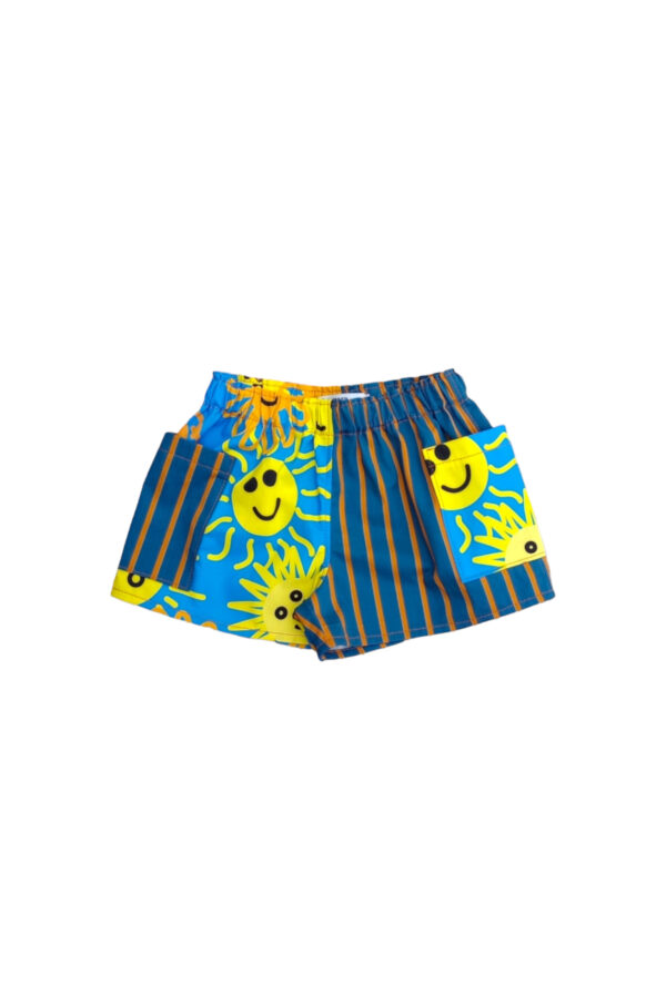 Alana kid's shorts blue feature fun print with sun faces all-over sky-blue background. One side of the shorts is done with stripey print in orange and dark blue.